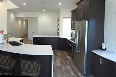 Eat-in kitchen - mid-sized transitional l-shaped brown floor eat-in kitchen idea in Other with an undermount sink, shaker cabinets, dark wood cabinets, stainless steel appliances and an island
