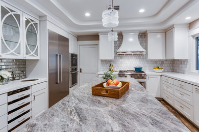Enclosed kitchen - large contemporary u-shaped medium tone wood floor and brown floor enclosed kitchen idea in Sacramento with a farmhouse sink, shaker cabinets, white cabinets, solid surface countertops, white backsplash, marble backsplash, stainless steel appliances, an island and white countertops