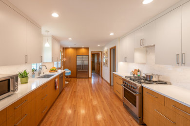 Example of a mid-sized 1960s galley medium tone wood floor and brown floor kitchen pantry design in Minneapolis with a single-bowl sink, flat-panel cabinets, light wood cabinets, quartz countertops, white backsplash, ceramic backsplash, stainless steel appliances, no island and white countertops