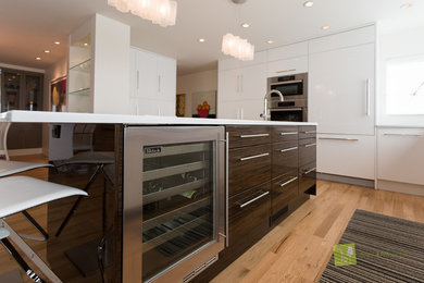 Large modern u-shaped eat-in kitchen in Calgary with a double-bowl sink, flat-panel cabinets, white cabinets, quartz benchtops, white splashback, glass sheet splashback, stainless steel appliances, light hardwood floors and with island.