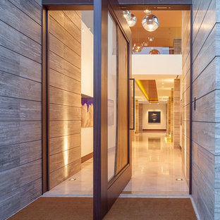 Esempio di un'ampia porta d'ingresso contemporanea con pareti beige, pavimento in granito, una porta a pivot e una porta in legno bruno