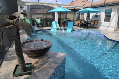 Hot tub - large tropical backyard tile and custom-shaped hot tub idea in Orlando