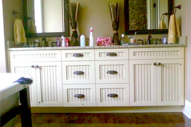 Example of a mid-sized classic master medium tone wood floor freestanding bathtub design in Charlotte with a drop-in sink, louvered cabinets, white cabinets, granite countertops and beige walls
