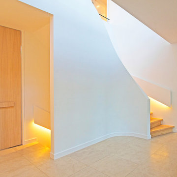 Viertelgewendelte Betontreppe mit Stufen in Eiche und geschwungener Innenwand