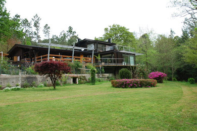 Large country brown two-story wood house exterior photo in Other with a gambrel roof and a mixed material roof