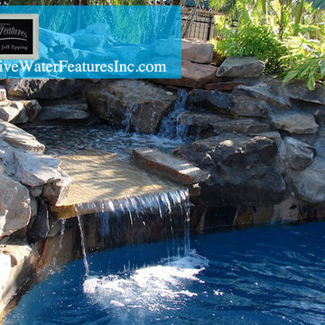 Tropical backyard room with pool waterfall, fireplace, and koi pond