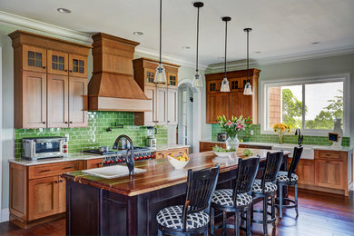 Kitchen - craftsman l-shaped dark wood floor and brown floor kitchen idea in Huntington with a farmhouse sink, shaker cabinets, medium tone wood cabinets, wood countertops, green backsplash, subway tile backsplash, stainless steel appliances, an island and brown countertops