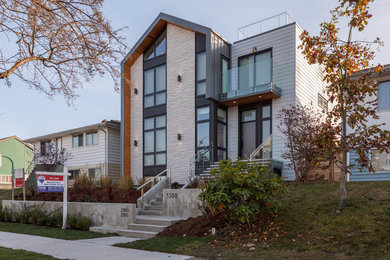 This is an example of a large contemporary three-storey concrete duplex exterior in Vancouver with a gable roof and a metal roof.