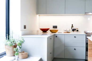 Design ideas for a large modern u-shaped open plan kitchen in London with an integrated sink, flat-panel cabinets, green cabinets, quartzite benchtops, white splashback, stone slab splashback, stainless steel appliances, cement tiles, with island, grey floor and white benchtop.