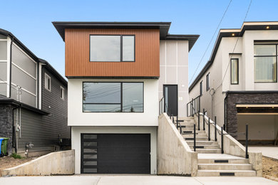 Example of a huge minimalist multicolored two-story mixed siding flat roof design in Calgary