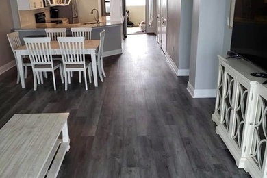 Example of a mid-sized beach style formal and open concept vinyl floor and gray floor living room design in Miami with gray walls, no fireplace and a tv stand