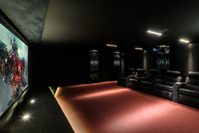 Ejemplo de cine en casa cerrado de tamaño medio con paredes negras, moqueta y pantalla de proyección