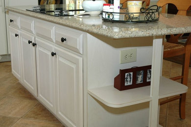 Eat-in kitchen - mid-sized traditional l-shaped light wood floor and beige floor eat-in kitchen idea in DC Metro with an undermount sink, raised-panel cabinets, white cabinets, granite countertops, black appliances and an island