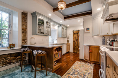Large farmhouse l-shaped dark wood floor enclosed kitchen photo in Philadelphia with glass-front cabinets, blue cabinets, quartzite countertops, white backsplash, white appliances, a peninsula and white countertops