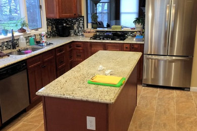 Mid-sized transitional u-shaped porcelain tile eat-in kitchen photo in St Louis with a double-bowl sink, shaker cabinets, medium tone wood cabinets, granite countertops, gray backsplash, glass sheet backsplash, stainless steel appliances and an island
