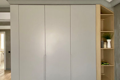 Imagen de armario y vestidor unisex actual de tamaño medio con a medida, armarios con paneles lisos, puertas de armario grises, suelo laminado, suelo naranja y vigas vistas