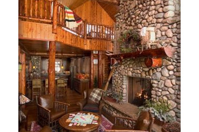 Example of a large mountain style open concept dark wood floor and brown floor living room design in Minneapolis with brown walls, a standard fireplace, a stone fireplace and no tv