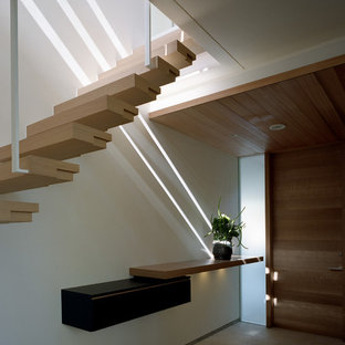 Foto de vestíbulo moderno con paredes blancas, puerta simple y puerta de madera en tonos medios