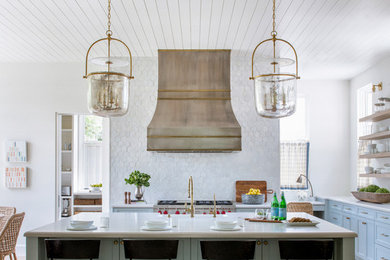 Kitchen - transitional l-shaped medium tone wood floor and brown floor kitchen idea in Dallas with a farmhouse sink, shaker cabinets, gray cabinets, white backsplash, stainless steel appliances, an island and white countertops