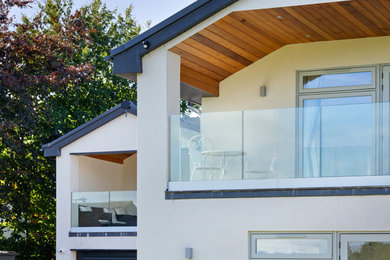 Expansive modern private glass railing balcony in West Midlands with a roof extension.