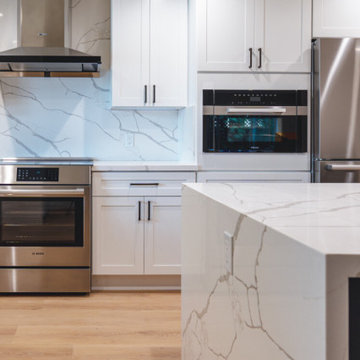 Modern White Shaker Kitchen with Navy Blue Island and Waterfall Quartz Counterto