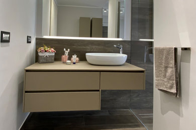Immagine di una stretta e lunga stanza da bagno padronale design di medie dimensioni con ante lisce, ante beige, doccia a filo pavimento, piastrelle in gres porcellanato, pareti grigie, pavimento in gres porcellanato, lavabo a bacinella, top in legno, porta doccia a battente, top beige, mobile bagno sospeso e soffitto ribassato