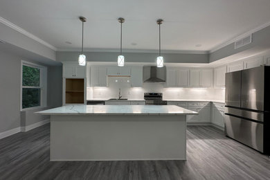 Kitchen - large vinyl floor and gray floor kitchen idea in Atlanta with a drop-in sink, shaker cabinets, white cabinets, quartz countertops, white backsplash, ceramic backsplash, stainless steel appliances, an island and white countertops