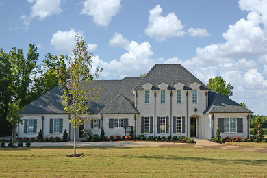 Inspiration for a large transitional beige two-story stucco house exterior remodel in Other with a hip roof and a shingle roof