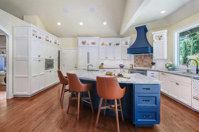 Large transitional l-shaped medium tone wood floor, brown floor and vaulted ceiling open concept kitchen photo in San Francisco with an undermount sink, recessed-panel cabinets, blue cabinets, quartzite countertops, white backsplash, subway tile backsplash, stainless steel appliances, an island and multicolored countertops
