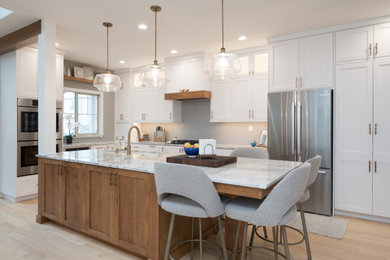 Transitional l-shaped light wood floor and beige floor kitchen photo in Boise with an undermount sink, shaker cabinets, white cabinets, gray backsplash, stainless steel appliances, an island and gray countertops
