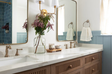 Example of a mid-sized country blue tile and ceramic tile vinyl floor and double-sink bathroom design in Orange County with beaded inset cabinets, medium tone wood cabinets, blue walls, quartz countertops, white countertops, a niche and a built-in vanity