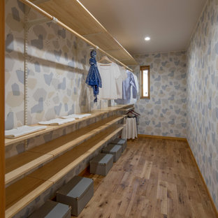 Ispirazione per una cabina armadio per donna scandinava di medie dimensioni con pavimento in legno massello medio, soffitto in carta da parati e pavimento marrone