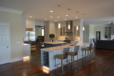 Example of a large classic u-shaped dark wood floor and brown floor eat-in kitchen design in Other with a double-bowl sink, recessed-panel cabinets, gray cabinets, quartzite countertops, glass tile backsplash, stainless steel appliances, two islands and multicolored backsplash