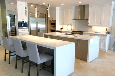 Design ideas for a mid-sized transitional galley open plan kitchen in Miami with an undermount sink, shaker cabinets, white cabinets, solid surface benchtops, white splashback, marble splashback, stainless steel appliances, travertine floors, multiple islands and beige floor.