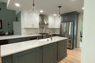 Inspiration for a mid-sized transitional galley light wood floor and brown floor kitchen remodel in Atlanta with a farmhouse sink, shaker cabinets, gray cabinets, quartz countertops, gray backsplash, porcelain backsplash, stainless steel appliances, an island and white countertops