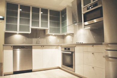 Enclosed kitchen - mid-sized contemporary l-shaped light wood floor and beige floor enclosed kitchen idea in Vancouver with an undermount sink, flat-panel cabinets, white cabinets, solid surface countertops, gray backsplash, stone slab backsplash, stainless steel appliances and no island