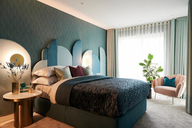 Photo of a large contemporary master bedroom in London with green walls, carpet, grey floors and wallpapered walls.