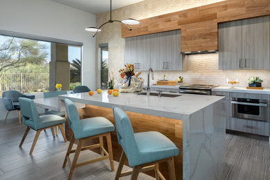 Eat-in kitchen - mid-sized 1950s galley porcelain tile and gray floor eat-in kitchen idea in Phoenix with a single-bowl sink, flat-panel cabinets, light wood cabinets, quartz countertops, beige backsplash, porcelain backsplash, stainless steel appliances, an island and white countertops