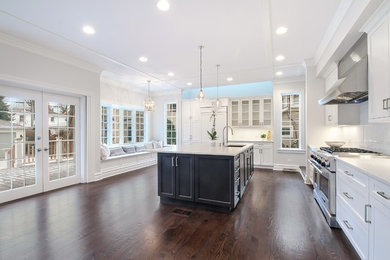 Inspiration for a large transitional l-shaped dark wood floor eat-in kitchen remodel in Chicago with quartz countertops, white backsplash, paneled appliances, an island, a double-bowl sink, shaker cabinets, subway tile backsplash and white cabinets