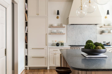 Example of a large minimalist l-shaped medium tone wood floor and brown floor open concept kitchen design in Atlanta with an undermount sink, beaded inset cabinets, beige cabinets, granite countertops, white backsplash, marble backsplash, paneled appliances, an island and multicolored countertops
