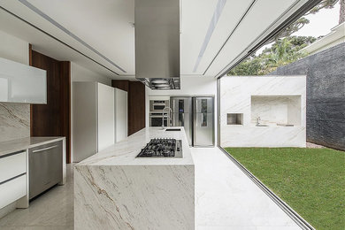 Eat-in kitchen - large modern l-shaped marble floor and white floor eat-in kitchen idea in Atlanta with an undermount sink, flat-panel cabinets, white cabinets, marble countertops, white backsplash, marble backsplash, stainless steel appliances and an island
