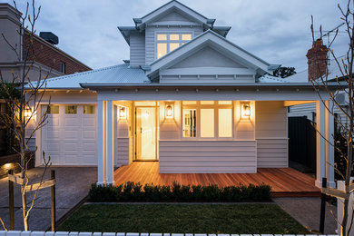 Photo of a mid-sized traditional two-storey white house exterior in Melbourne with wood siding and a metal roof.