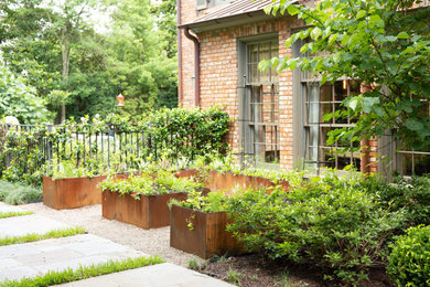 Imagen de jardín clásico de tamaño medio en patio delantero con jardín francés, macetero elevado, exposición parcial al sol y gravilla