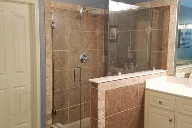 Alcove shower - mid-sized traditional 3/4 brown tile and ceramic tile ceramic tile and brown floor alcove shower idea in Atlanta with raised-panel cabinets, white cabinets, gray walls, an undermount sink, quartzite countertops and a hinged shower door