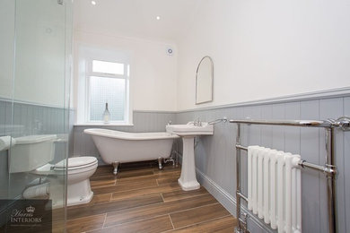 Klassisches Badezimmer mit freistehender Badewanne, offener Dusche, grauer Wandfarbe, Keramikboden, Sockelwaschbecken, braunem Boden und Falttür-Duschabtrennung in Sonstige