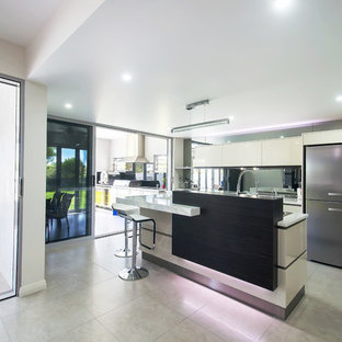 Design ideas for a large contemporary galley kitchen pantry in Brisbane with a double-bowl sink, flat-panel cabinets, white cabinets, laminate benchtops, metallic splashback, mirror splashback, stainless steel appliances, porcelain floors and with island.