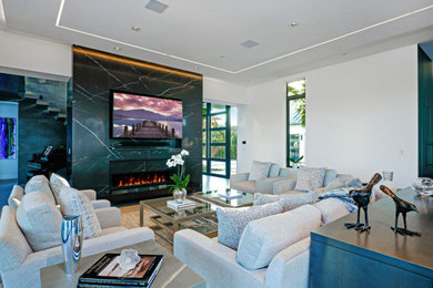 This is an example of a contemporary living room in Miami with white walls, a ribbon fireplace and a wall-mounted tv.