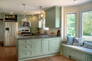 Inspiration for a mid-sized craftsman u-shaped medium tone wood floor and brown floor eat-in kitchen remodel in Other with a farmhouse sink, shaker cabinets, green cabinets, quartz countertops, white backsplash, subway tile backsplash, stainless steel appliances, a peninsula and gray countertops