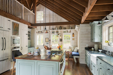 Example of a mid-sized mountain style u-shaped medium tone wood floor eat-in kitchen design in Boston with a farmhouse sink, raised-panel cabinets, blue cabinets, soapstone countertops, black backsplash, stone slab backsplash, stainless steel appliances and an island