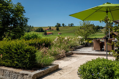 Kleiner Country Garten im Sommer mit direkter Sonneneinstrahlung und Natursteinplatten in Sonstige